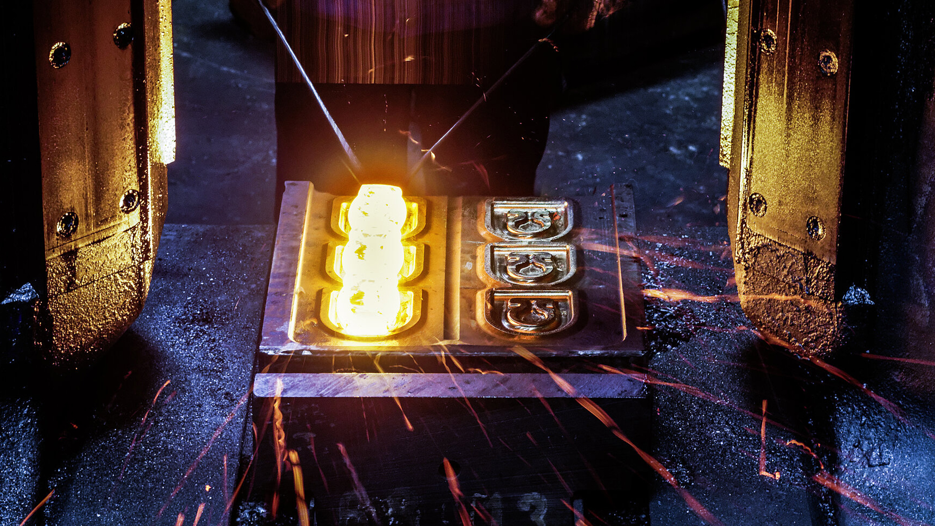 Heißer Schmiedeprozess: Glühendes Metall wird in eine Form gepresst, Funken sprühen.