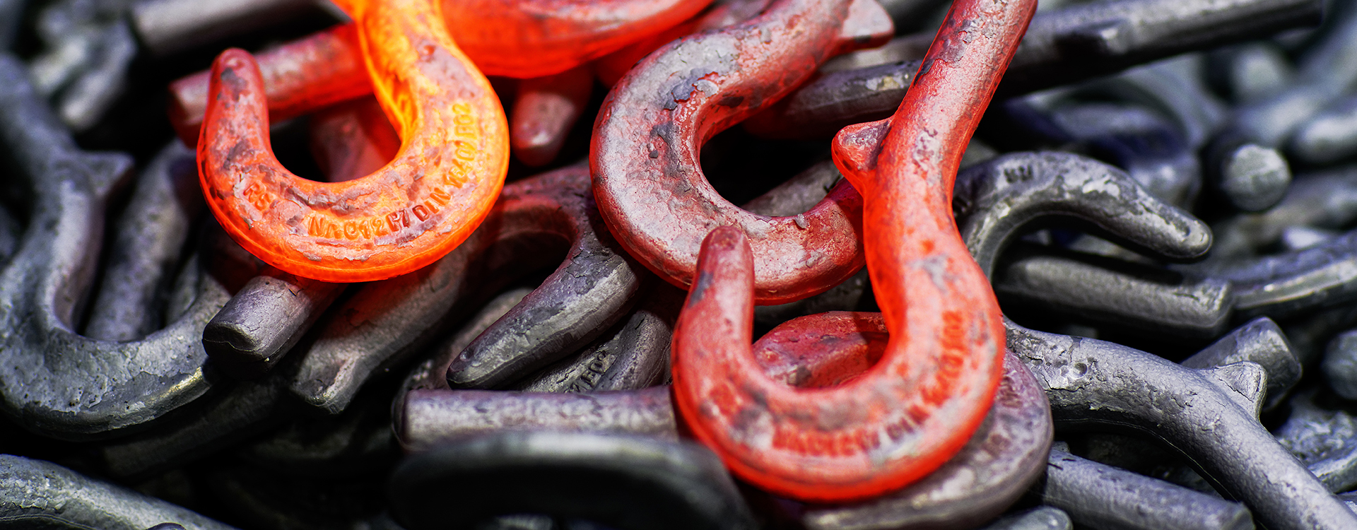 Glühende Lasthaken liegen auf einem Haufen erkalteter Lasthaken.